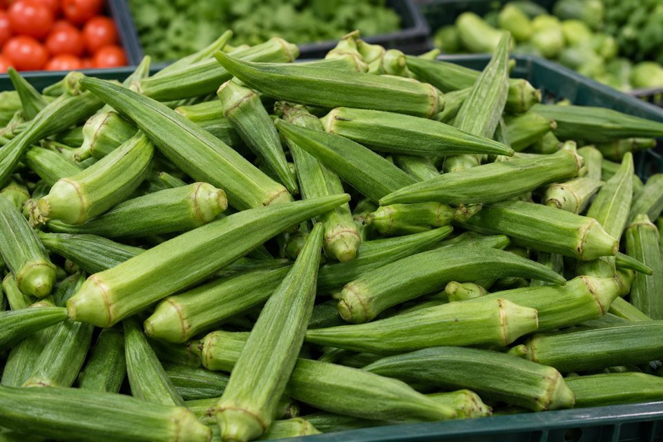Fresh green okra pods in a produce crate